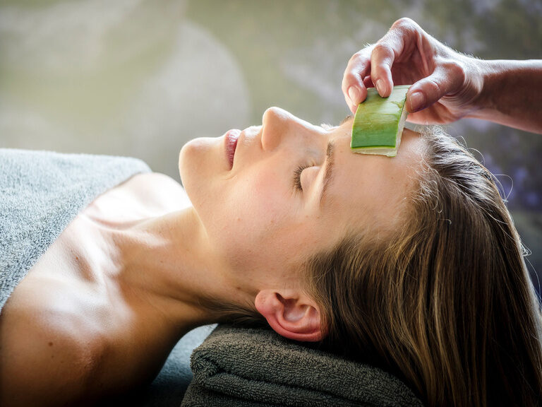 Kosmetikerin bestreicht ausgestreckten Arm einer Kundin mit einer Körperpackung