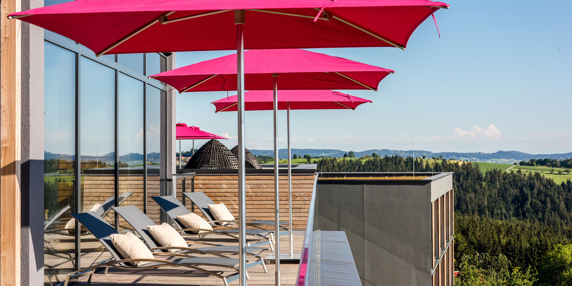 Liegen und Sonnenschirme auf dem Balkon des Hotel Hüttenhof Bayern