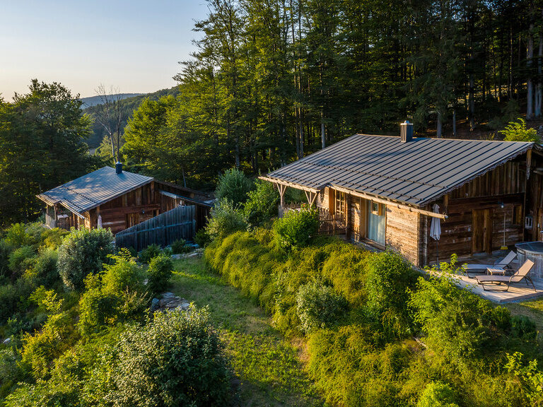 Beleuchteter, blauer Innenpool in der Dämmerung mit Panoramablick auf Bayerischen Wald