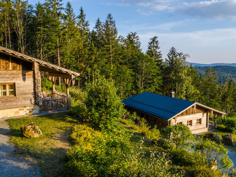 Beleuchteter, blauer Innenpool in der Dämmerung mit Panoramablick auf Bayerischen Wald