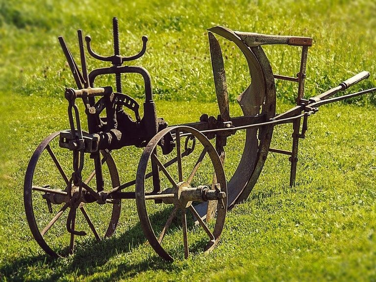 Blauer, beleuchteter Außenpool, umgeben von Liegen und Sonnenschirmen auf grüner Wiese
