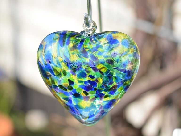 Blauer, beleuchteter Außenpool, umgeben von Liegen und Sonnenschirmen auf grüner Wiese