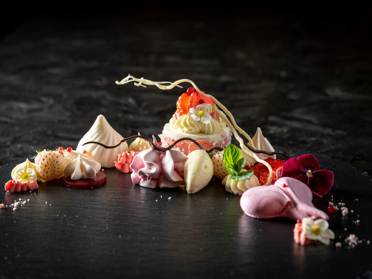 Blauer, beleuchteter Außenpool, umgeben von Liegen und Sonnenschirmen auf grüner Wiese