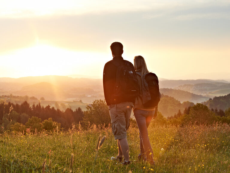Frau sitzt auf sonniger Wiese im Bayerischen Wald