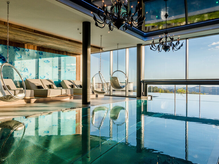 Innenpool mit großen Fensterfronten mit Blick auf den Bayerischen Wald, Gemütliche Liegen und Hängesessel