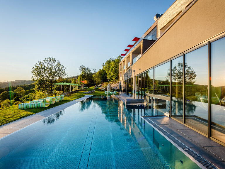 Lächelndes Paar genießt Panorama im Außenpool vom 4-Sterne-Luxushotel Hüttenhof