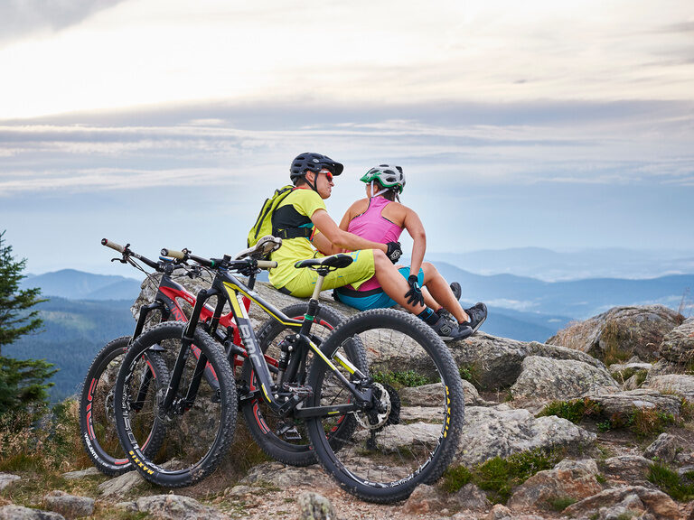 Zwei Mountainbiker machen eine Pause und haben eine tolle Aussicht auf den Bayerwald rund um Bodenmais.