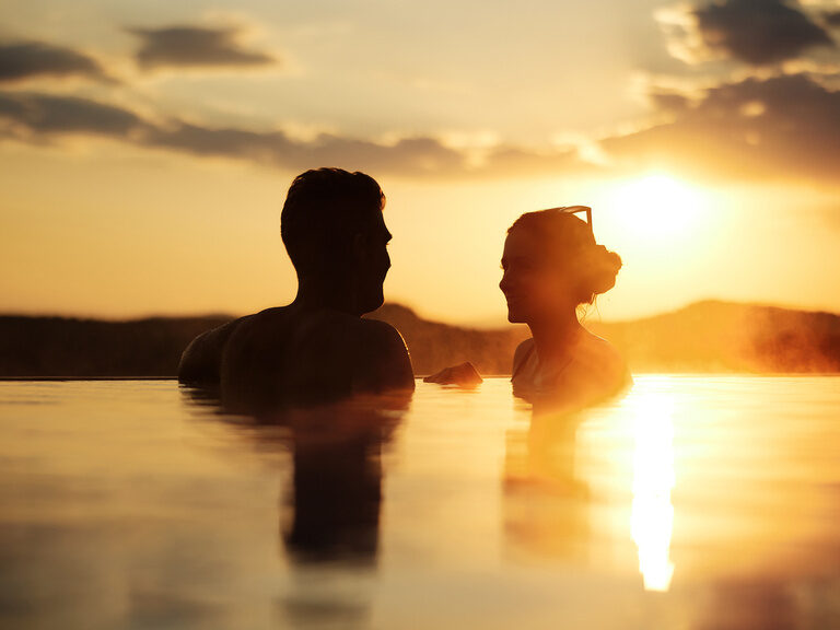 Paar in Schattenansicht bei goldener Dämmerung im Dachpool im Hotel Hüttenhof