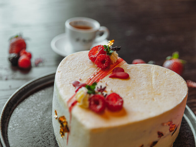 Paar sitzt lachend in Lounge-Bereich und stößt mit zwei Sektgläsern an