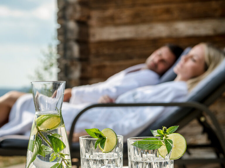Pärchen genießt die Sonne auf den Liegen des Luxus Chalets Bayerischer Wald im Bergdorf Hüttenhof