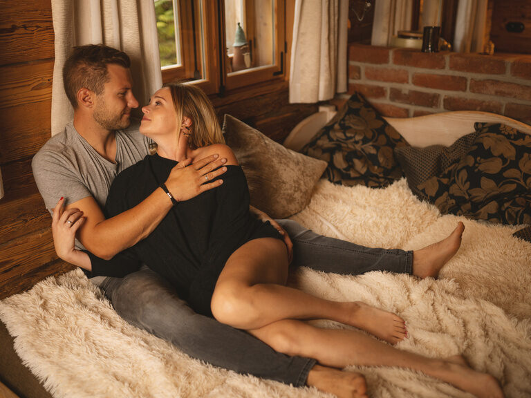 Pärchen liegt gemeinsam im Bett und sieht sich an - Luxuschalet Bayern