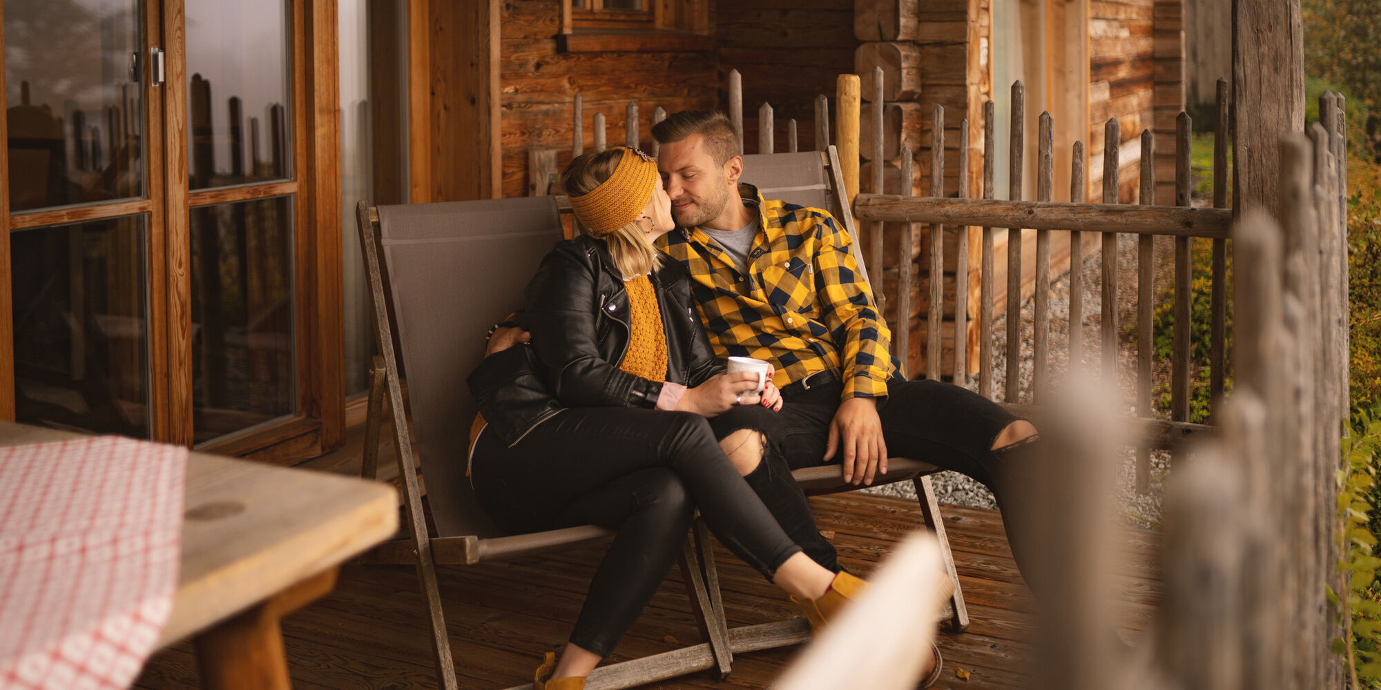 Pärchen sitzt gemeinsam auf Terrasse des Luxus Chalets Bayern