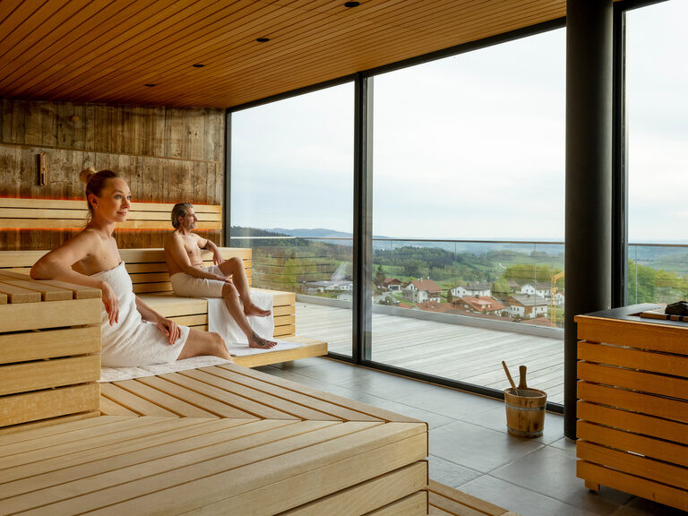 Pool auf sonniger Dachterrasse mit Sonnenschirmen und Waldpanorama vom Hotel Hüttenhof