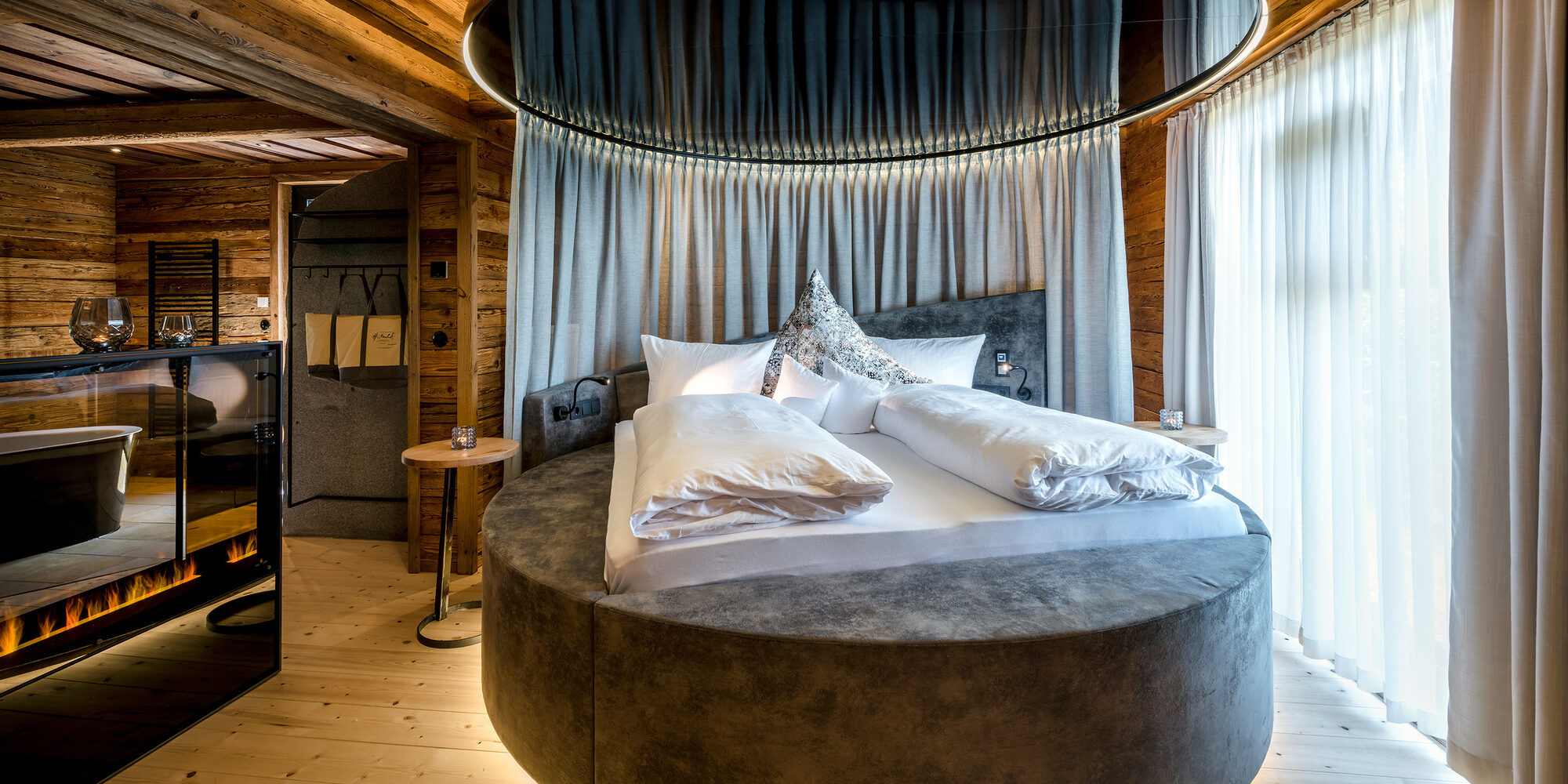 Schlafzimmer mit rundem Bett und freistehender Badewanne im Luxus Chalet Bayerischer Wald
