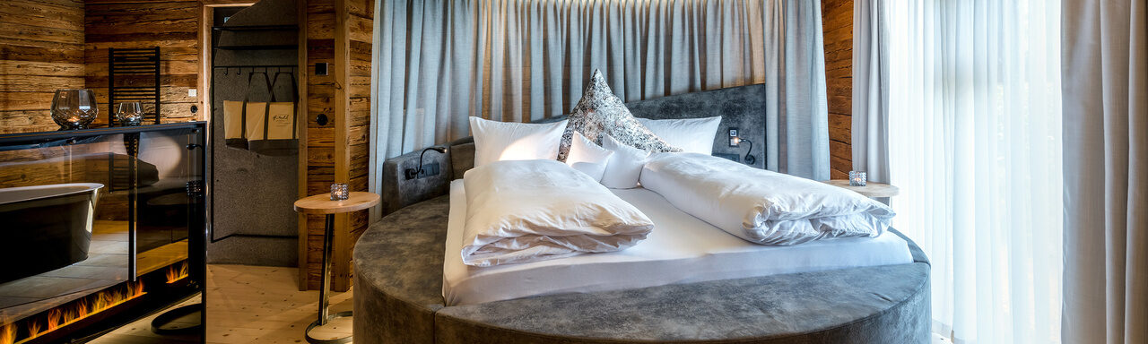 Schlafzimmer mit rundem Bett und freistehender Badewanne im Luxus Chalet Bayerischer Wald