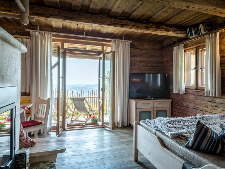 Zimmer mit gemütlichen Doppelbett, freistehender Badewanne und Ledersitz im Vordergrund des Hotel Hüttenhof